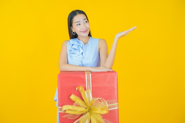 Porträt schöne junge asiatische Frau Lächeln mit roter Geschenkbox auf Gelb
