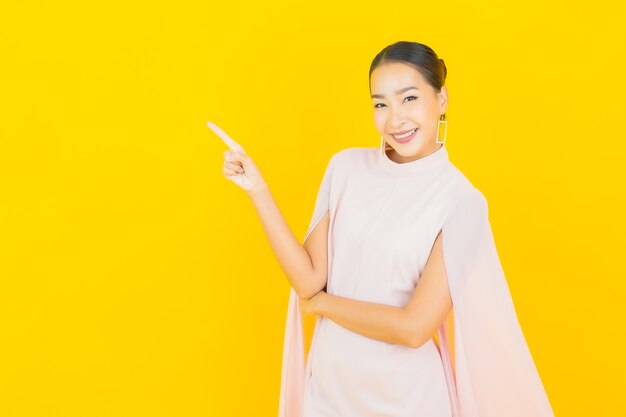 Porträt schöne junge asiatische Frau lächeln mit vielen Aktion auf gelber Wand