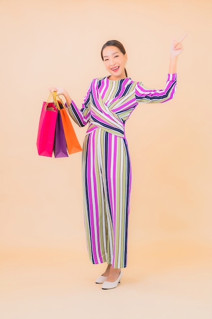 Porträt schöne junge asiatische Frau mit bunter Einkaufstasche auf Farbe