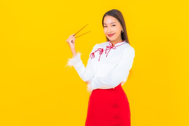 Porträt schöne junge asiatische Frau mit Essstäbchen essfertig auf Gelb