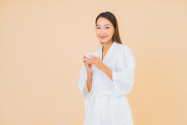 Porträt schöne junge asiatische Frau mit Kaffeetasse auf Beige