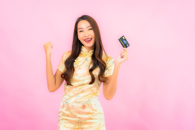 Porträt schöne junge asiatische Frau mit Kreditkarte und Handy auf rosa Farbe Wand