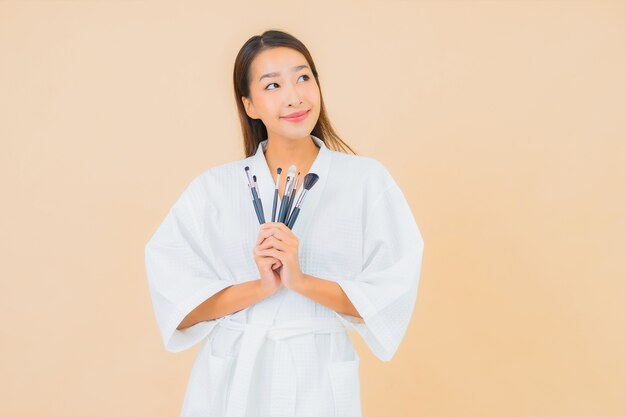 Porträt schöne junge asiatische Frau mit Make-up Pinsel auf Beige