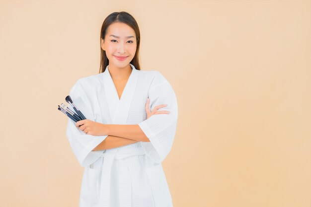 Porträt schöne junge asiatische Frau mit Make-up Pinsel auf Beige