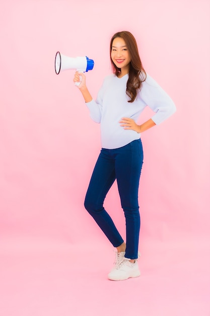 Porträt schöne junge asiatische Frau mit Megaphon für Kommunikation auf rosa isolierte Wand