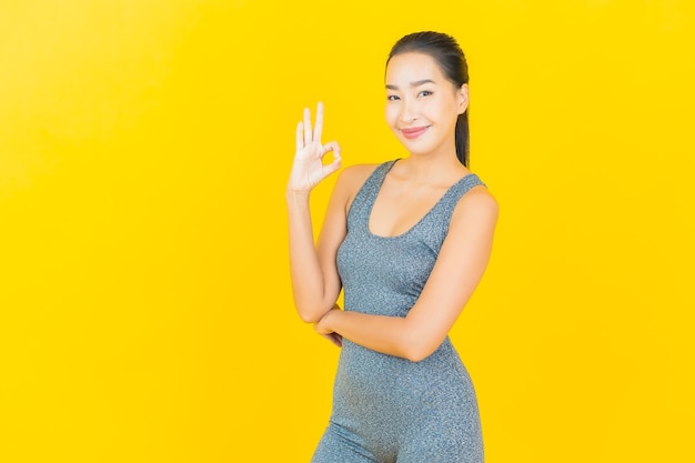 Porträt schöne junge asiatische Frau mit Sportbekleidung bereit für Übung auf gelber Wand