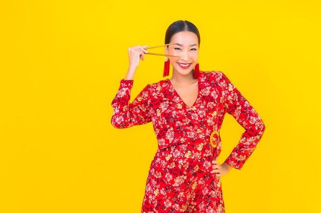 Porträt schöne junge asiatische Frau mit Stäbchen auf Farbe isolierte Wand