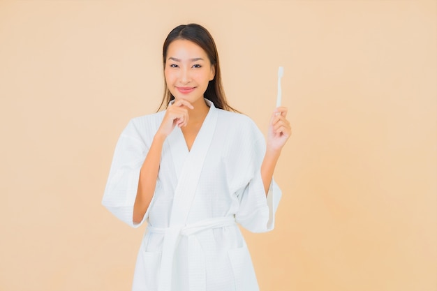 Porträt schöne junge asiatische Frau mit Zahnbürste auf Beige