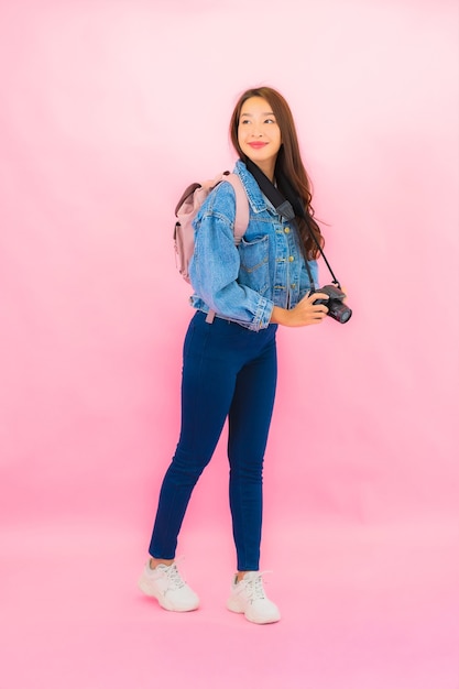 Porträt schöne junge asiatische Frau Rucksack oder Gepäck mit Kamera bereit für die Reise im Urlaub auf rosa Wand