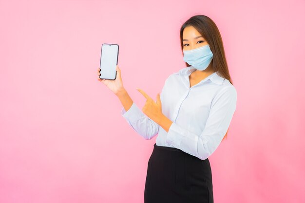 Porträt schöne junge asiatische frau trägt maske zum schutz vor covid19 und coronavirus an rosa wand