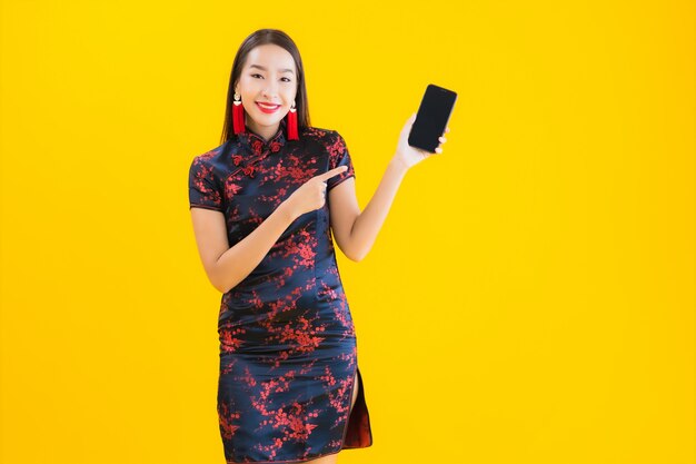 Porträt schöne junge asiatische Frau tragen chinesisches Kleid verwenden Smart-Handy