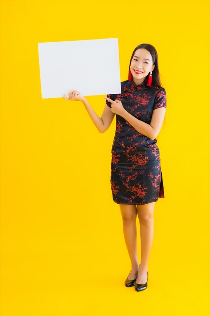Porträt schöne junge asiatische Frau tragen chinesisches Kleid zeigen weiße leere Plakatwand