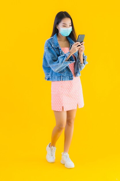 Porträt schöne junge asiatische Frau tragen Maske verwenden Smartphone