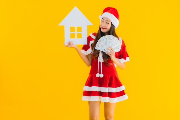 Porträt schöne junge asiatische Frau tragen Weihnachtskleidung und Hut zeigen Haus Haus Zeichen