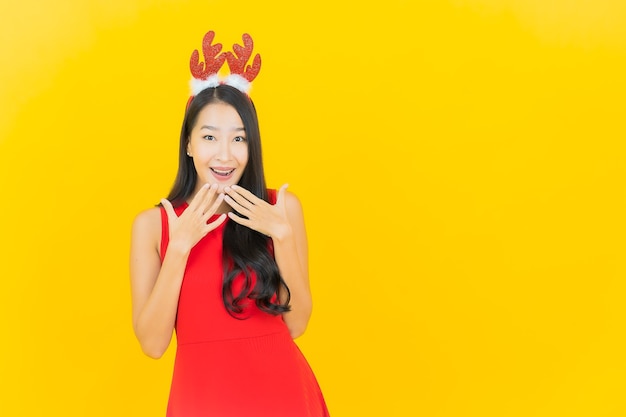 Porträt schöne junge asiatische Frau tragen Weihnachtsmütze oder Haarband auf gelber Wand