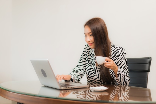Porträt schöne junge asiatische Frau verwenden Computer Laptop auf Arbeitstisch im Raum