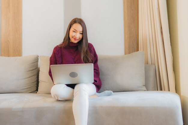 Porträt schöne junge asiatische Frau verwenden Computer Laptop auf Sofa im Wohnzimmer Interieur