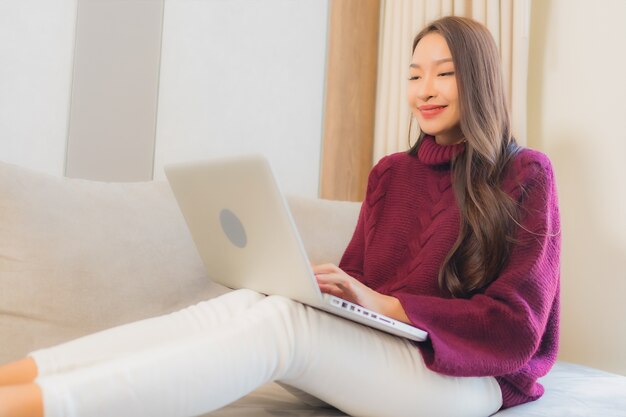 Porträt schöne junge asiatische Frau verwenden Computer Laptop auf Sofa im Wohnzimmer Interieur