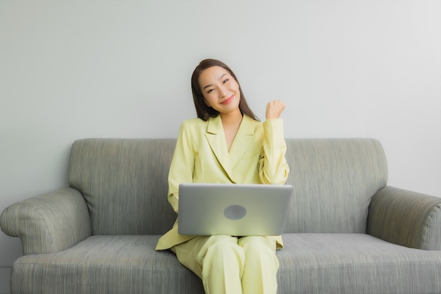 Porträt schöne junge asiatische Frau verwenden Computer Laptop auf Sofa im Wohnzimmer Interieur