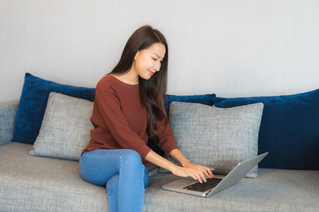 Porträt schöne junge asiatische Frau verwenden Computer Laptop auf Sofa im Wohnzimmer Interieur