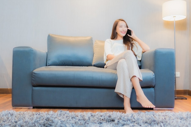 Porträt schöne junge asiatische Frau verwenden intelligentes Handy auf Sofa im Wohnzimmer Interieur