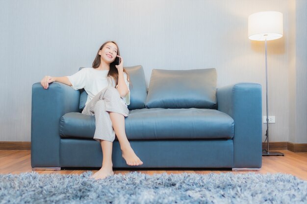 Porträt schöne junge asiatische Frau verwenden intelligentes Handy auf Sofa im Wohnzimmer Interieur