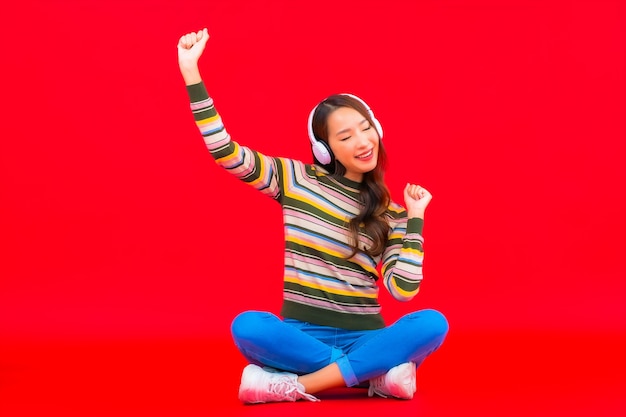 Porträt schöne junge asiatische Frau verwenden intelligentes Mobiltelefon mit Kopfhörer, um Musik zu hören