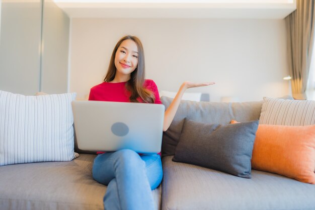 Porträt schöne junge asiatische Frau verwenden Laptop-Computer auf Sofa im Wohnbereich