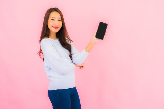 Porträt schöne junge asiatische Frau verwenden Smartphone auf rosa Farbe isolierte Wand