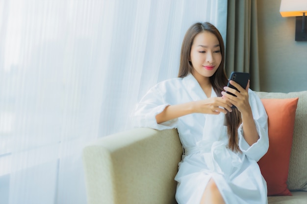 Porträt schöne junge asiatische Frau verwenden Smartphone auf Sofa