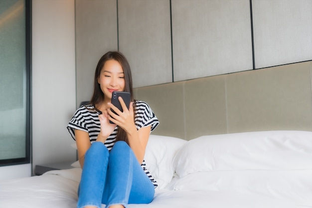 Porträt schöne junge asiatische Frau verwenden Smartphone im Schlafzimmer