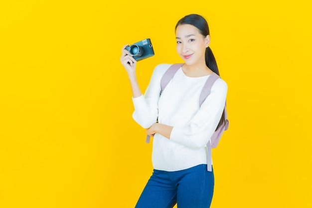 Porträt schöne junge asiatische Frau verwendet Kamera auf Gelb