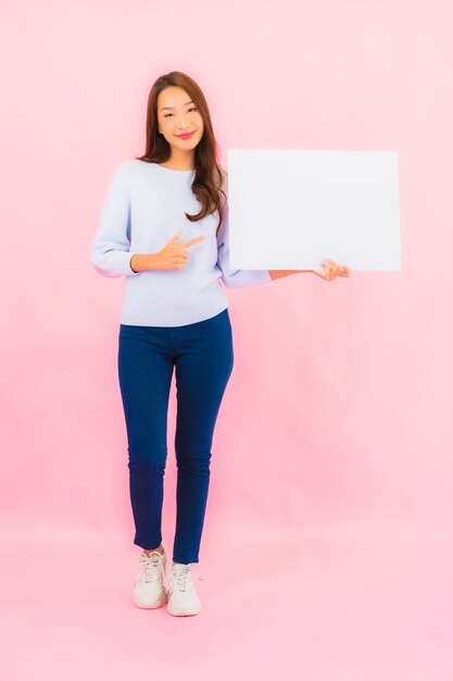 Porträt schöne junge asiatische Frau zeigen leere weiße Werbetafel für Text auf rosa Farbe Wand