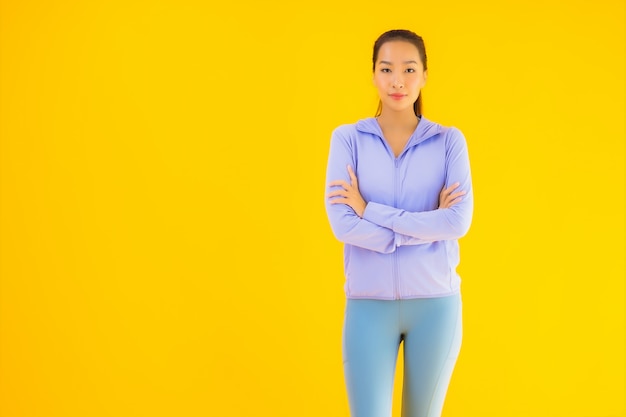 Porträt schöne junge asiatische Sportfrau bereit für Übung auf gelb