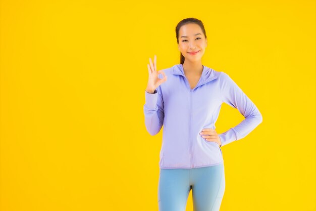 Porträt schöne junge asiatische Sportfrau bereit für Übung auf gelb