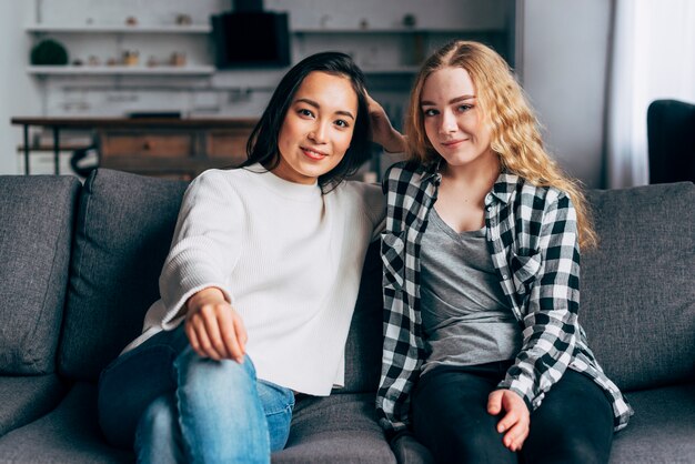 Kostenloses Foto porträt von den gemischtrassigen freundinnen, die auf couch sitzen