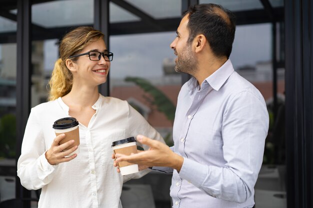 Porträt von den glücklichen Geschäftskollegen, die an der Kaffeepause sprechen