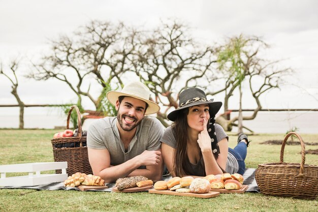 Kostenloses Foto porträt von den jungen paaren, die auf decke am picknick liegen
