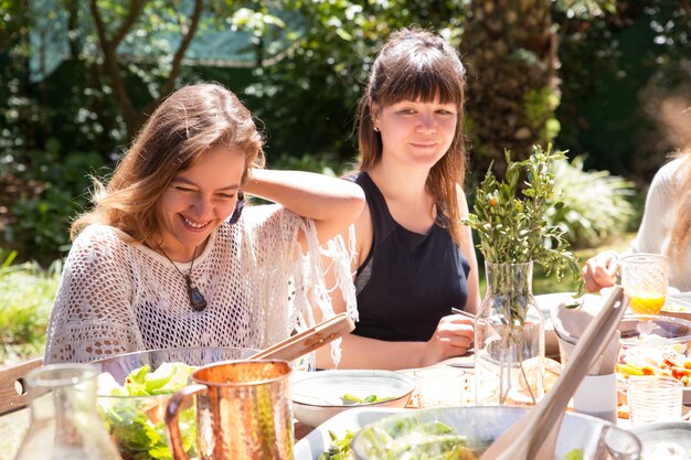 Porträt von den lächelnden Frauen, die zusammen am Gartenfest sitzen