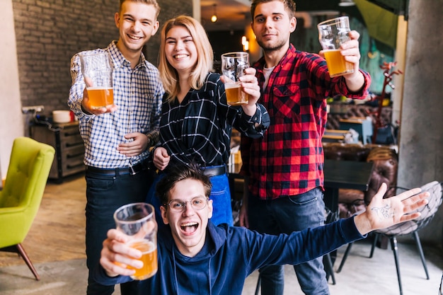 Porträt von den lächelnden Freunden, welche in der Hand die feiernden Biergläser halten