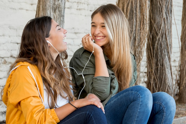 Porträt von den lächelnden Freundinnen, die Musik teilen