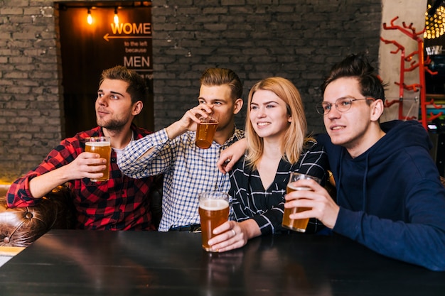 Porträt von den lächelnden jungen Freunden, die das Bier genießen