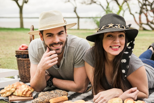 Porträt von den lächelnden jungen Paaren, die am Picknick genießen