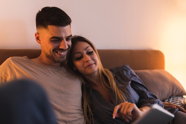 Porträt von den lächelnden reizenden jungen Paaren, die Laptop betrachten