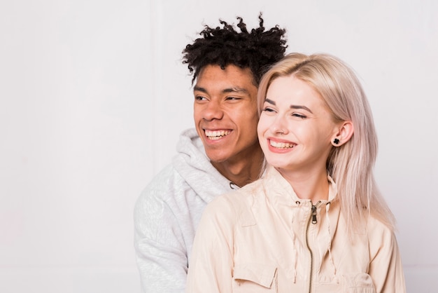 Porträt von den lächelnden zwischen verschiedenen Rassen jungen Paaren lokalisiert gegen weißen Hintergrund
