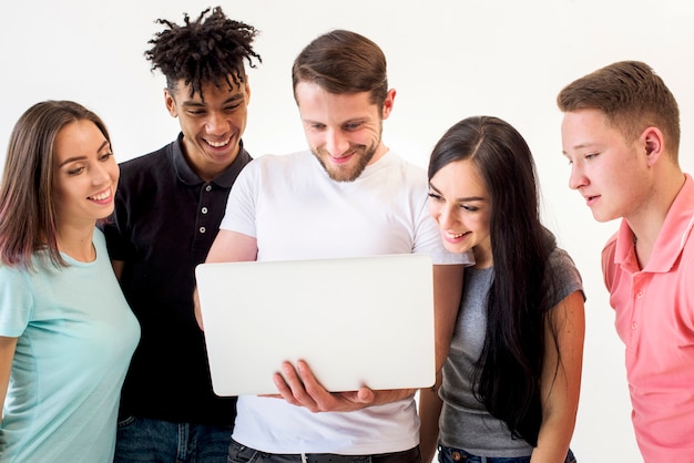 Porträt von den multiethnischen Freunden, die auf dem Laptop steht im weißen Hintergrund schauen