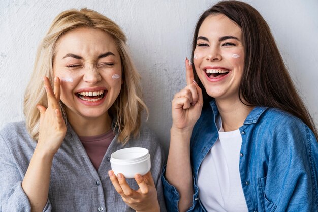 Porträt von Frauen, die lachen und mit Feuchtigkeitscreme spielen