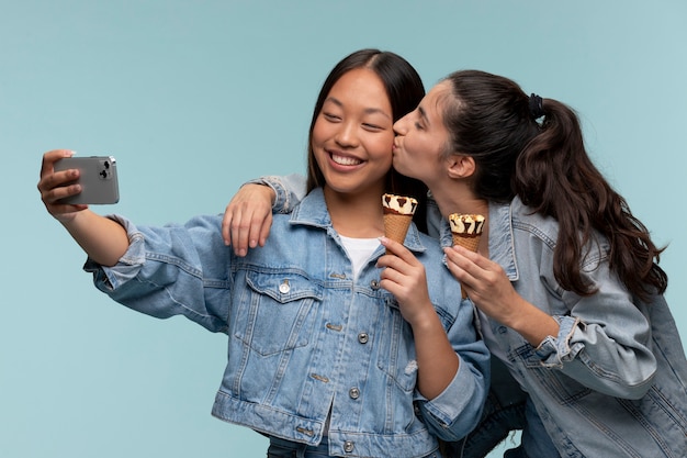 Porträt von jungen Mädchen im Teenageralter, die ein Selfie machen, während sie ein Eis halten