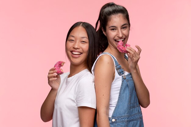 Porträt von jungen Mädchen im Teenageralter, die zusammen posieren und Donuts essen
