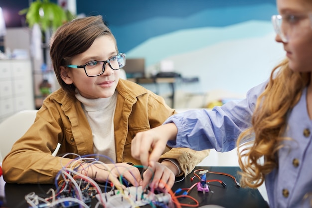 Porträt von jungen und mädchen, die roboter bauen und mit elektrischen schaltungen während des ingenieurunterrichts in der schule experimentieren, platz kopieren